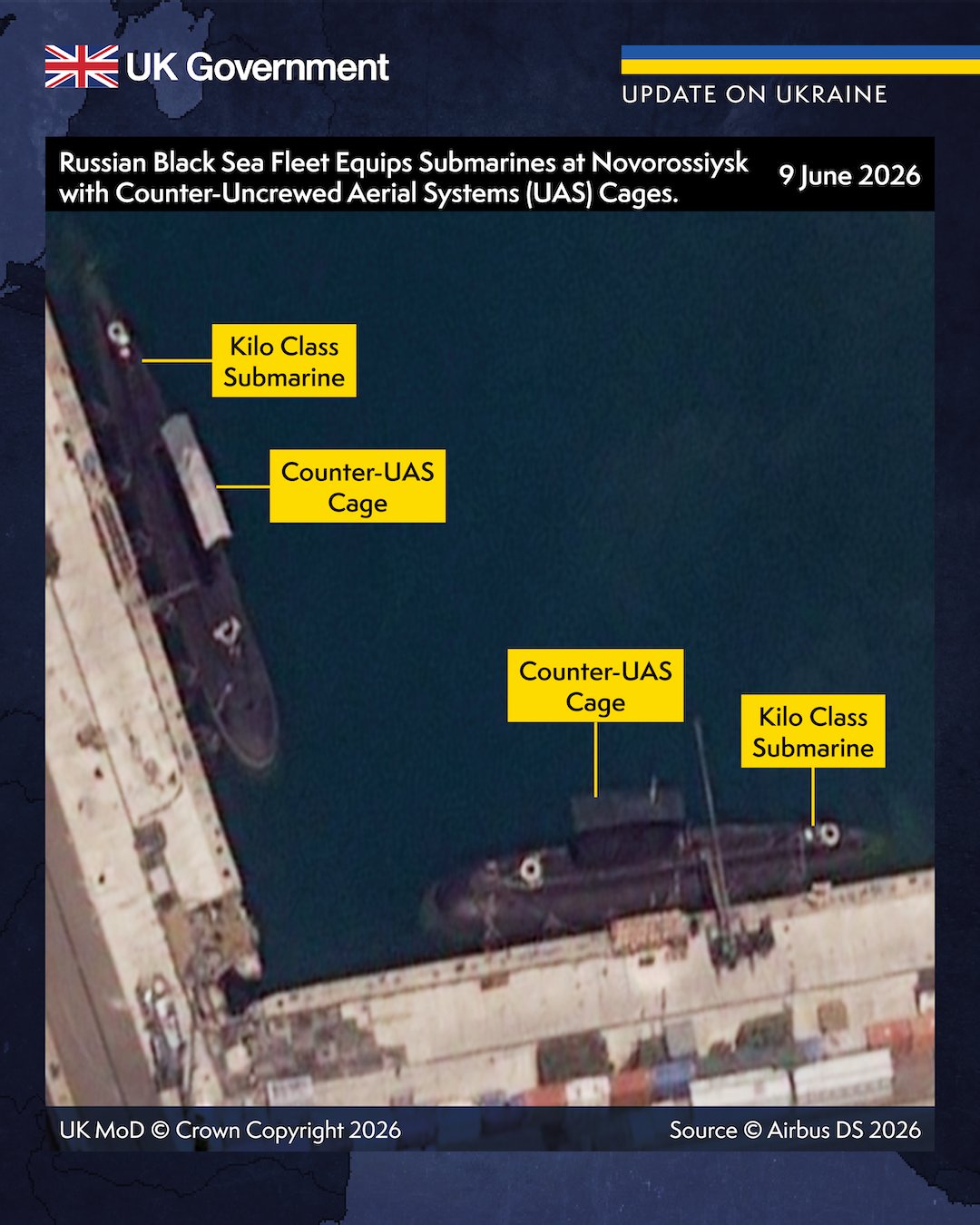 Official British Ministry of Defence graphic: a satellite image of two Kilo-class submarines alongside a quay at Novorossiysk, with yellow callouts labelling the boats and the pale box structures of counter-drone cages over their sails